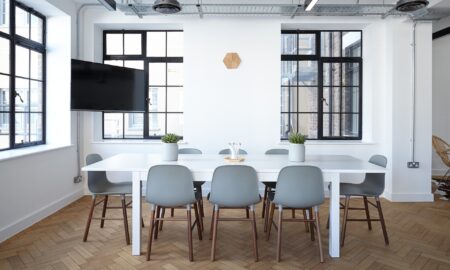 White table with green chairs surrounding it in white room with black framed windows